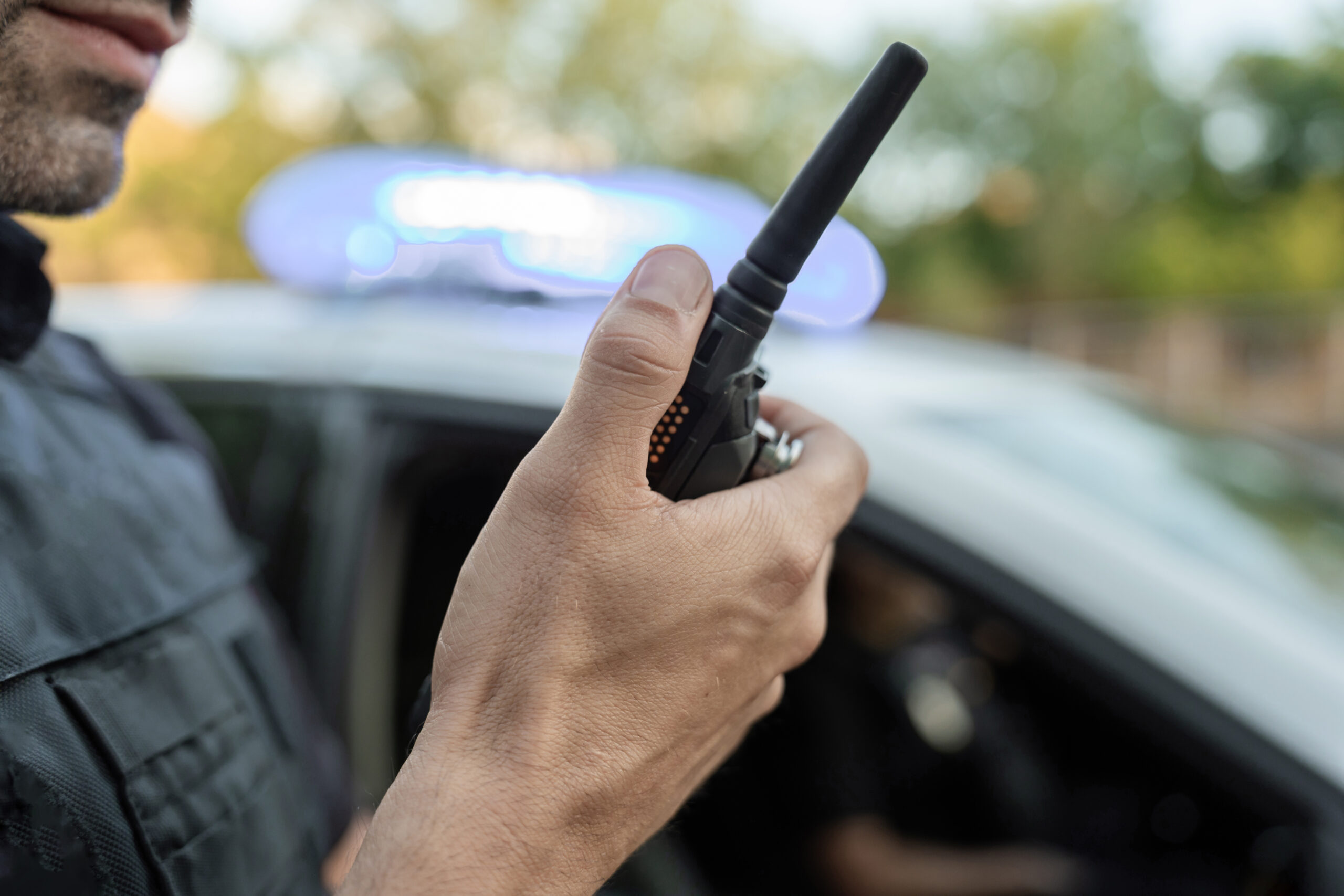Police,Officer,Is,Holding,A,Walkie,Talkie,Near,A,Patrol